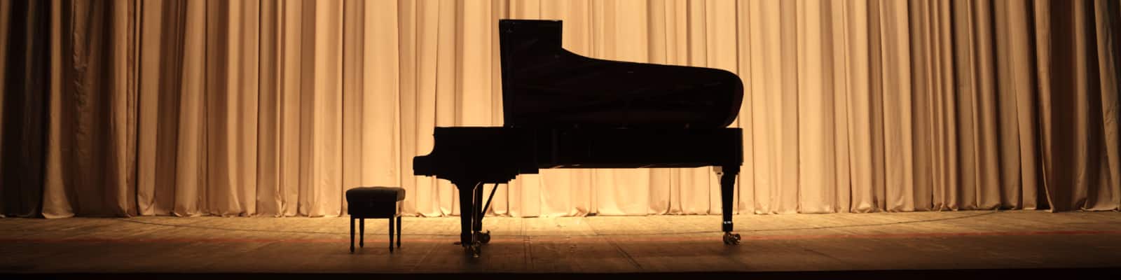 Grand piano at concert stage with brown curtain